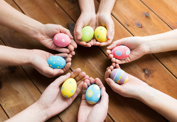 Hands holding colourful easter eggs form a circle