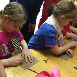 Two girls colouring brown paper.