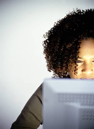 A girl sits in front of a laptop browsing the internet.